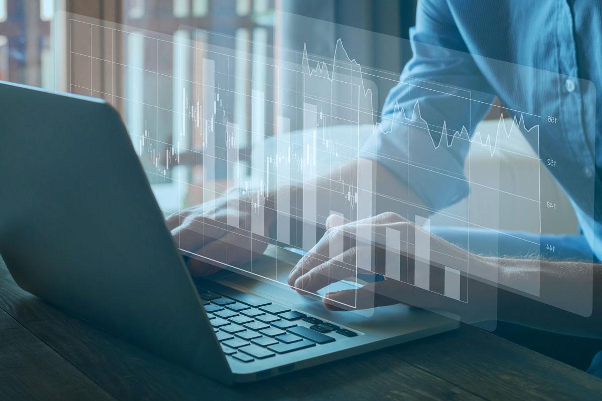 Hands typing on laptop with bar chart superimposed