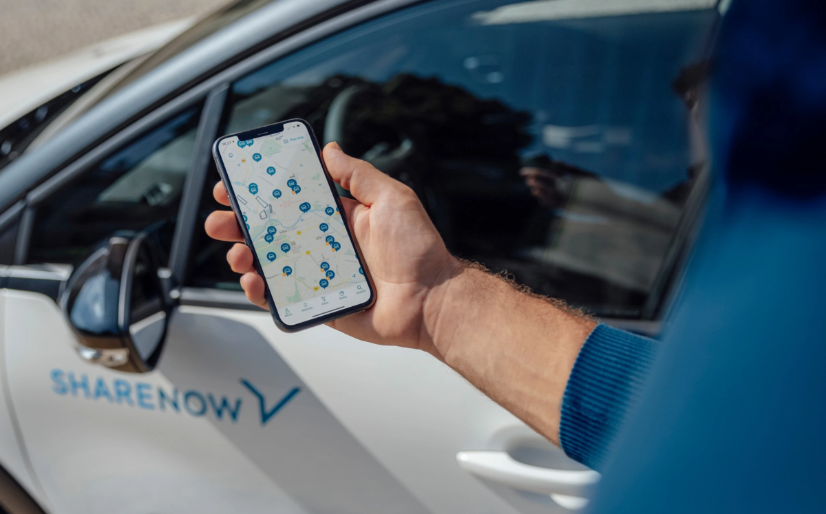Person looking at Share Now app next to a car