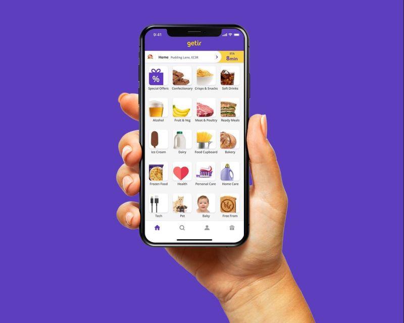 Person holds mobile phone with one hand, showing Getir app