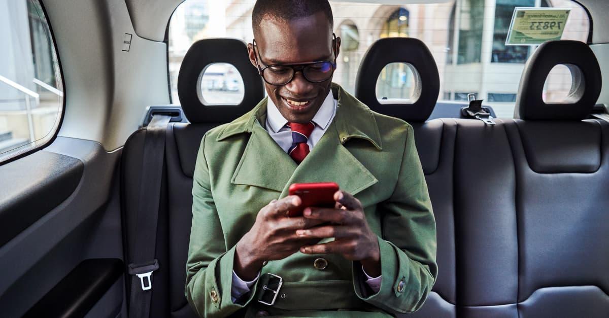 A passanger sits in a car on their mobile phone