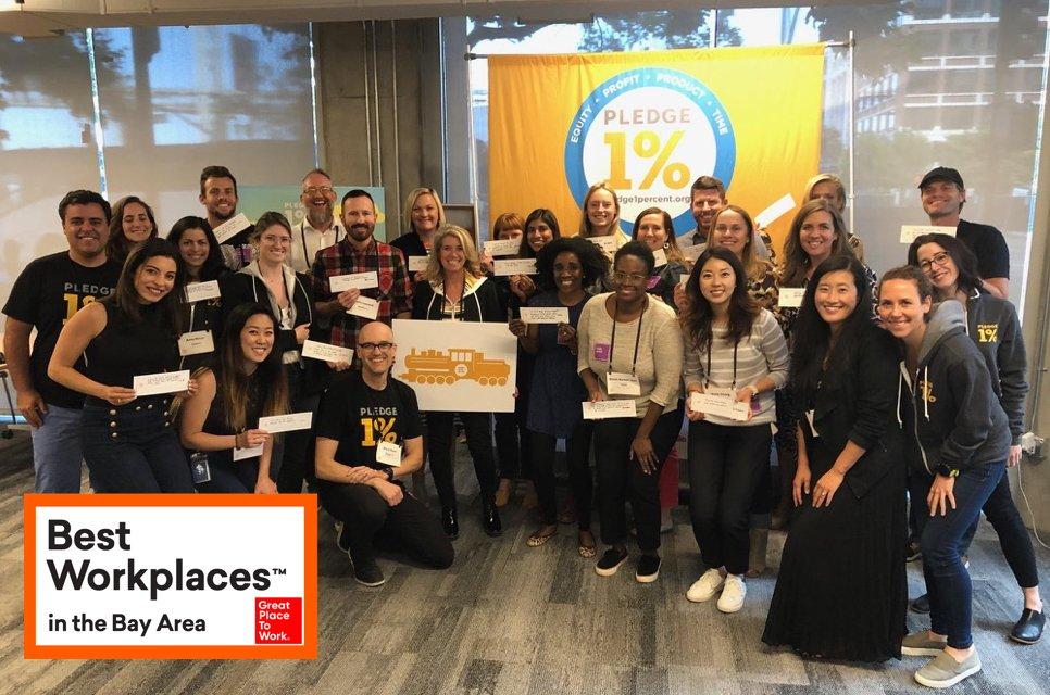 New Relic employees in front of "Pledge 1%" banner